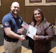 Michelle shaking Brandon's hand and holding American flag