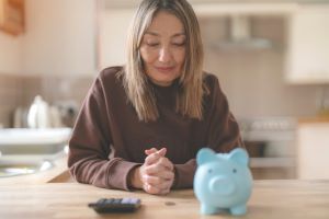 Woman budgeting with calculator and piggy bank