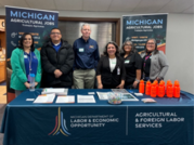 AFLS team standing behind tables with AFLS covers and banners