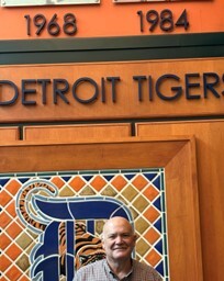 Don Drabik, a white man in glasses, standing in front of Detroit Tigers building sign