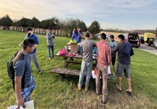 Group of people looking at materials on a table outside
