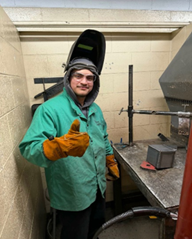 Eliseo wearing safety gear and holding his gloved thumb up