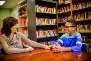 Guidance counselor and teenage boy in school library smiling