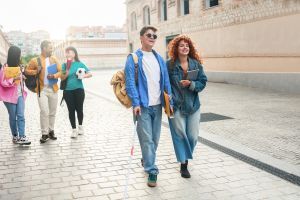 Blind young man walking with group of friends on a university campus