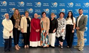 Zaman International team standing in front of banner