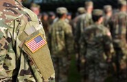 Close up of American flag patch on soldier's uniform with other soldiers in the background
