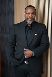 Gerod, a Black man wearing a black suit and glasses.