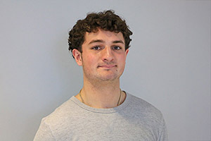 Brandon, a young, white man with curly hair wearing a white t-shirt