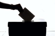 Silhouette of hand dropping a vote into a ballot box