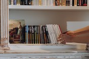 white bookshelf with Russian books and hands reaching forward