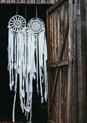 white dreamcatchers hanging in front of a wooden door