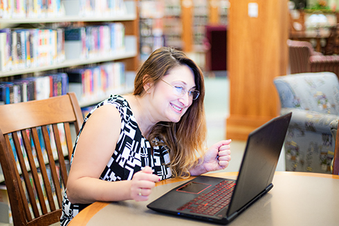 An educator using a laptop in a school library.