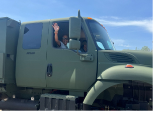 Passenger waving from a green military truck.
