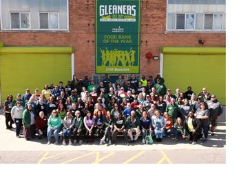 A large group of Gleaners volunteers and workers with a mural in the background reading: Gleaners - Food Bank of the Year