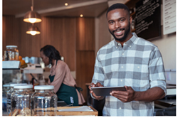 Photo of a happy veteran standing in his own coffee shop  