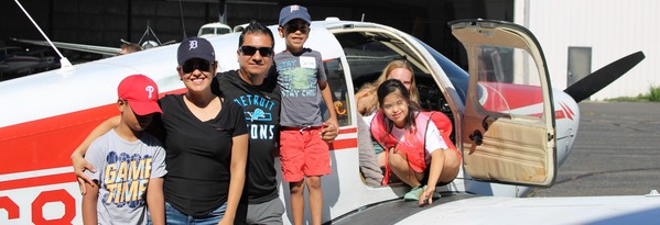 family standing in front of an airplane