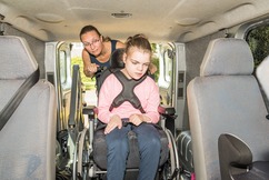 Mother taking child in a wheelchair out of a transportation van