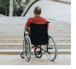 Man in a wheelchair looking at a stairway.