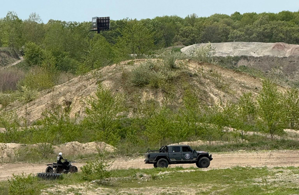 A wide shot of a Jeep and four-wheeler driving across the hilly terrain of the Holly Oaks ORV Park