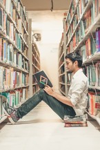 Guy reading a book in library