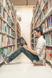 Guy reading a book in library