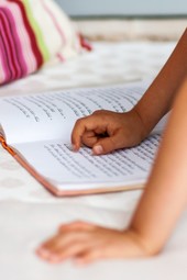 close up of a kids hand while they read a book