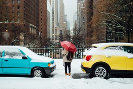 a person standing between two cars while its snowing
