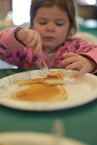 Child eating pancakes with syrup