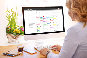 Woman typing on a computer that is displaying a calendar