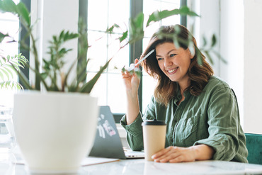 Woman with a coffee and a pen in front of a laptop