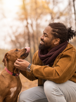 Young Black man petting a dog in the autumn