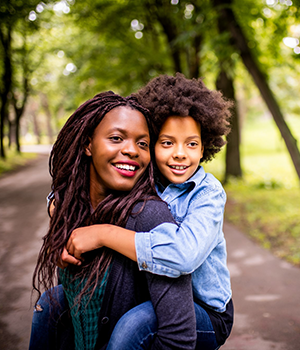 Woman with child on back, on wooded trail