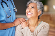 Doctor resting hand on shoulder of older woman patient