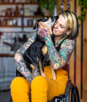 Woman with colorful tattoos petting a dog