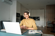 Woman at desk with headphone and laptop
