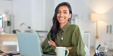 Smiling woman with long hair, laptop computer and drinking mug.