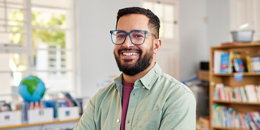 Man of color with bookshelf and window in background