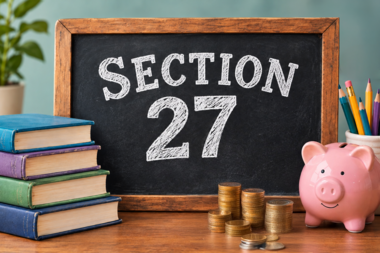 Chalkboard displaying “Section 27” beside stacked books, colored pencils, coins, and a pink piggy bank.  