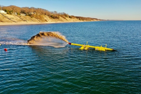 Photo showing long yellow dredging pipe in Lake Michigan.