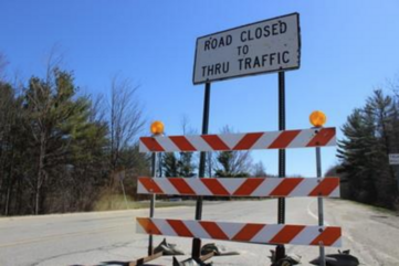 Road closed to thru traffic sign and construction barricade placed on a county road