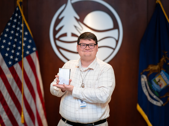 Sam Bode posed with award in front of the county logo.