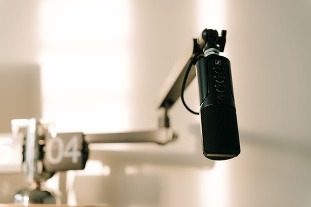A sleek professional microphone on a boom arm in a minimalist studio