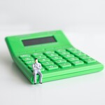 Miniature figure sitting on a calculator