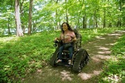 A woman uses the Track Chair to move along a trail