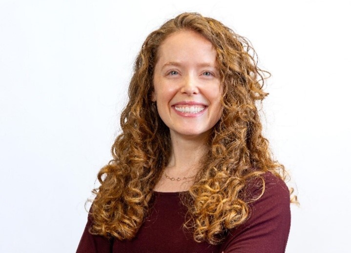 Alaina Gallagher, a smiling white woman with curly red hair, wearing a red shirt