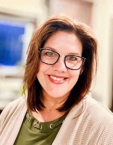 Jolene Juhl, a woman with brown hair and glasses wearing a cream sweater