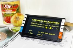 6" magnifier sitting on a cookbook, on the screen the text is enlarged and is yellow with a black background