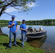 two men in holding tablets and getting ready to inspect a boat for aquatic invasive species 