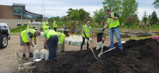 A pile of compost and people shoveling it into bags
