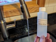 Photo of sample bottle with a faucet and water running 